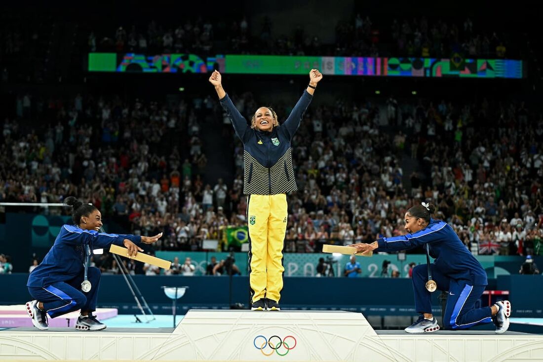 Foto de Rebeca Andrade sendo reverenciada por Simone Biles chama